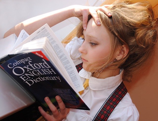 辞書を読みながら頭を押さえる女の子